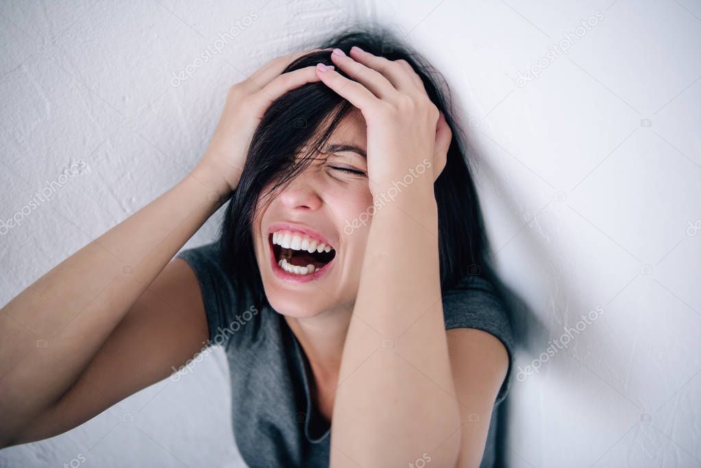 depressed brunette woman with hands on head screaming at home