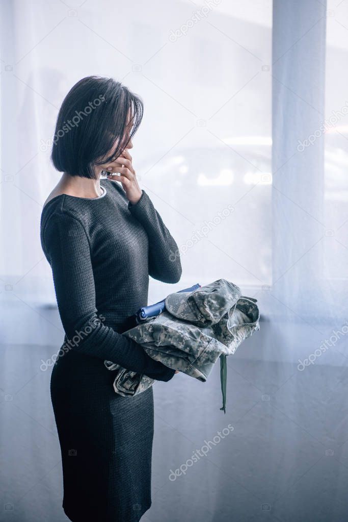 depressed woman holding military clothing at home