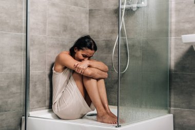 lonely worried woman sitting in shower at home clipart