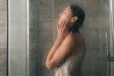 sad depressed woman in shower through glass with water drops clipart