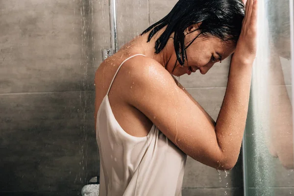 lonely frustrated woman covering face and crying in shower at home