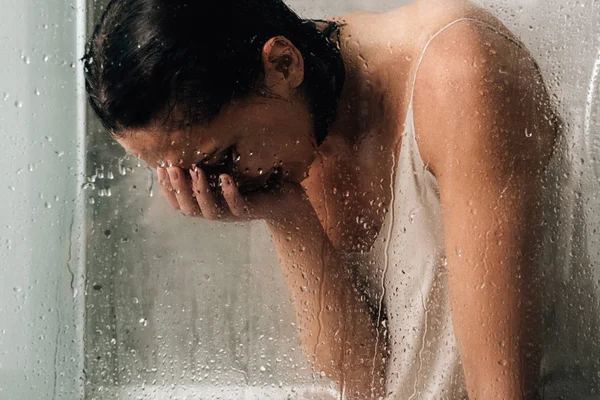 孤独的沮丧的女人哭在淋浴通过玻璃与水滴 — 图库照片