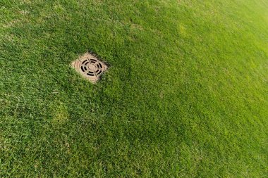 metallic manhole cover on green fresh grass  clipart