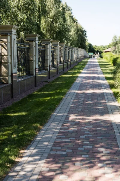 Walkway with paving stones near green grass and fence — Stock Image Walkway Paving Stones Green Grass Fence Stock Image