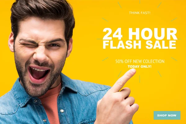 一个英俊的男人用手指指着24小时的闪光灯插画 在黄色的网上购物概念上眨了眨眼 — 图库照片