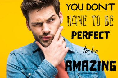 thoughtful handsome man touching chin isolated on yellow with you dont have to be perfect to be amazing inspiration clipart