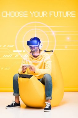 man on bean bag chair in virtual reality headset on yellow with cyberspace illustration and choose your future lettering clipart