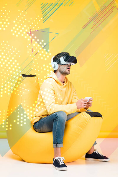 excited man on bean bag chair in virtual reality headset on yellow with cyberspace illustration