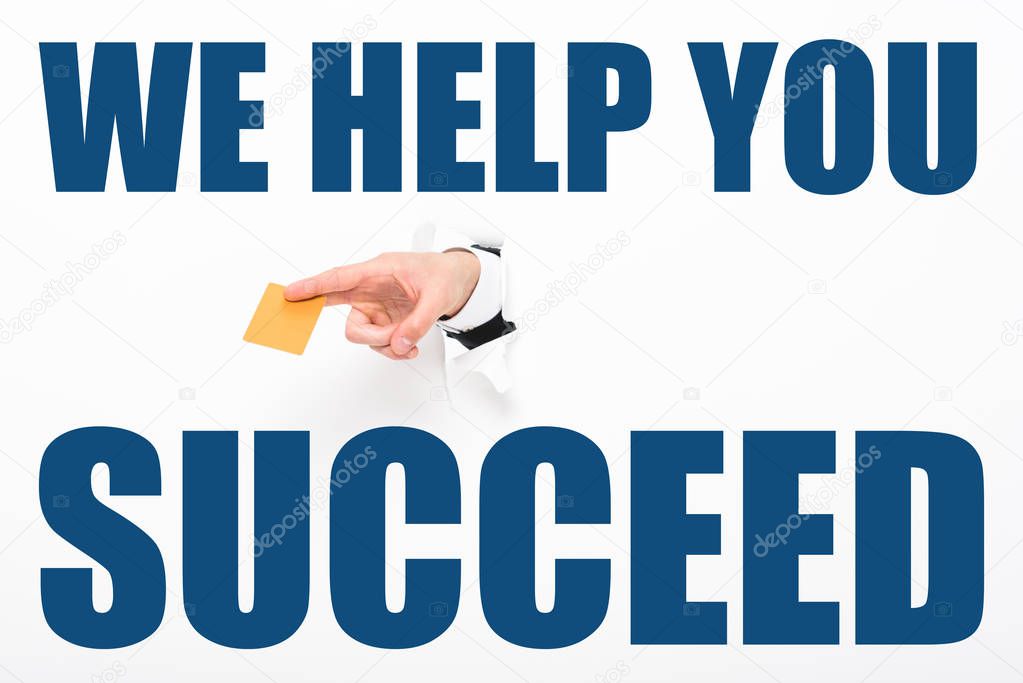 Cropped view of man holding empty business card from hole in white paper with we help you to succeed illustration