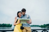 schöner Mann und asiatische Frau umarmen und Blick auf Karte 