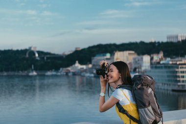 sırt çantası fotoğraf çeken asyalı kadının yan görünümü 