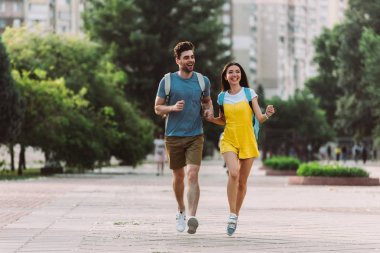 handsome man and asian woman running and looking away  clipart