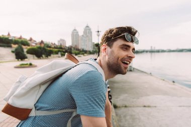 gözlüklü tişörtlü yakışıklı adam gülümseyerek ve uzağa bakıyor 