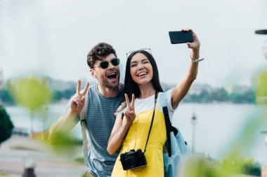 yakışıklı adam ve asya kadın barış işaretleri gösteren ve selfie alarak 