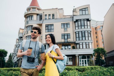 dijital kamera ve asyalı kadın gülümseyen ve kağıt bardak tutan adam 