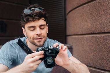 handsome man in glasses looking at digital camera outside  clipart
