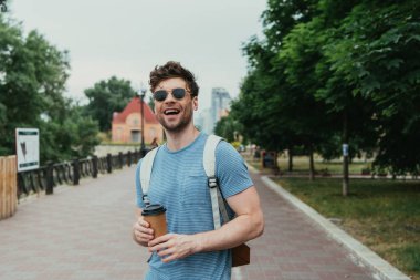  t-shirt kağıt bardak tutan yakışıklı adam ve uzağa bakıyor
