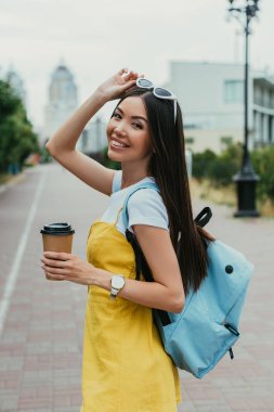  asyalı kadın kağıt bardak tutan ve kamera bakarak 