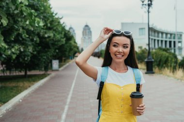  asyalı kadın kahve ile kağıt fincan tutarak ve uzağa bakarak 