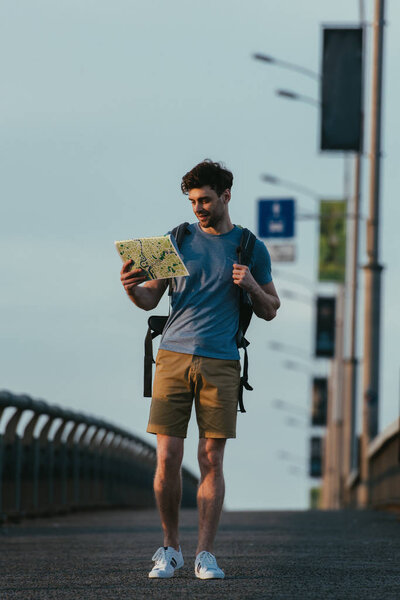 красивый мужчина в футболке и шортах смотрит на карту
 