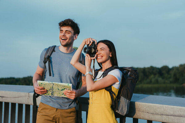 handsome man holding map and asian woman in overalls taking photo 