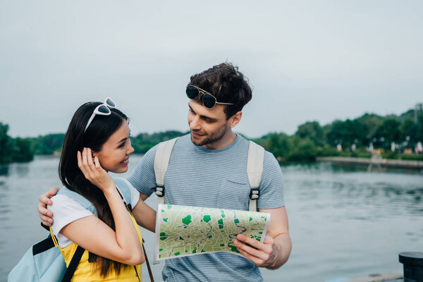 handsome man holding map and looking at asian woman