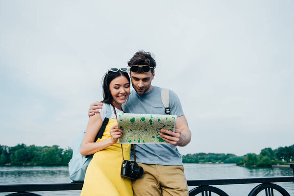 handsome man and asian woman hugging and looking at map 