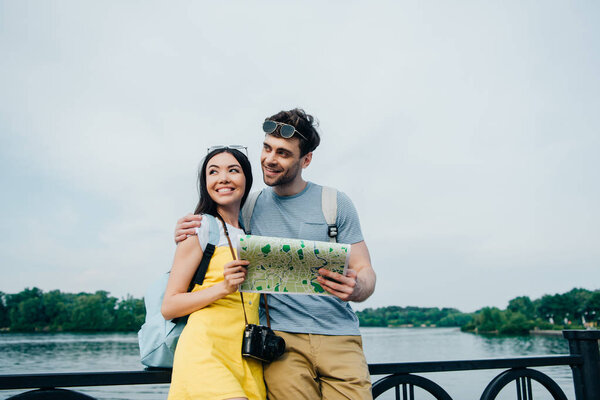 handsome man and asian woman hugging and looking away 