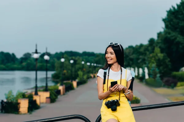 Asiatische Und Attraktive Frau Lächelt Und Hält Smartphone — Stockfoto