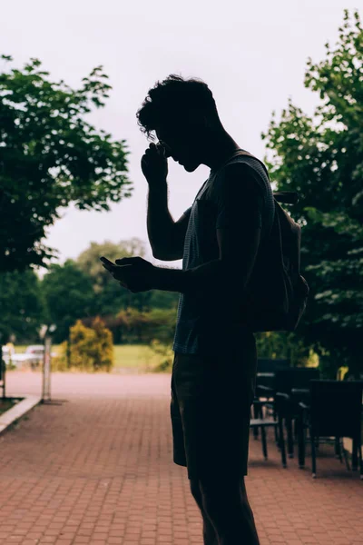 Silueta Hombre Con Mochila Usando Dispositivo Digital Exterior — Foto de Stock