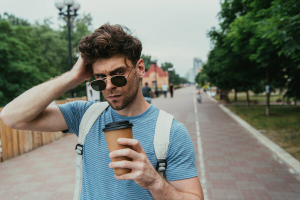 handsome man in t-shirt holding paper cup and looking away 