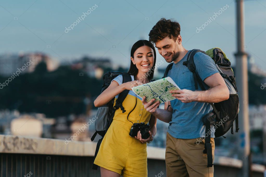 handsome man and asian woman smiling and looking at map