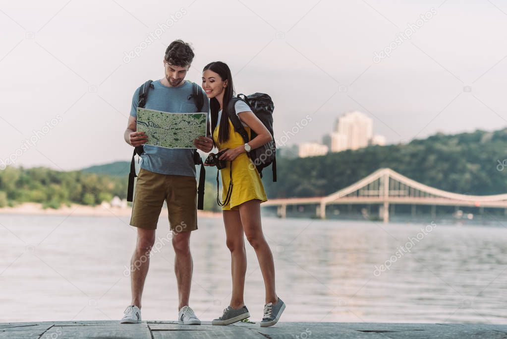 handsome man and asian woman in overalls looking at map 