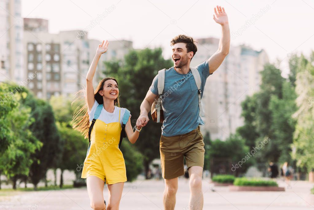 handsome man and asian woman running and waving outside 