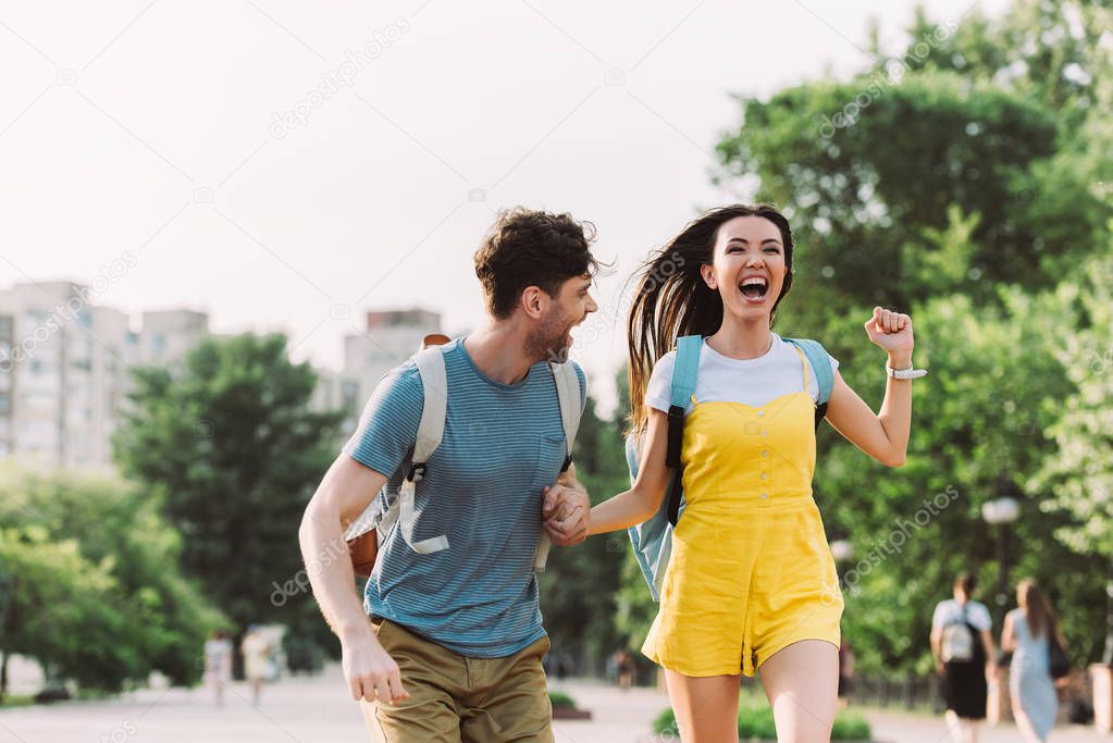 handsome man and asian woman running and looking away 