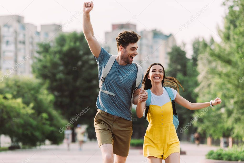 handsome man and asian woman running and showing yes gesture 