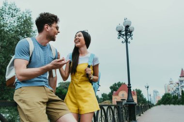 yakışıklı adam ve asyalı kadın gülümseyerek ve birbirlerine bakıyor 