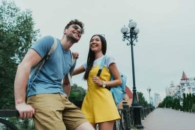 yakışıklı adam ve asyalı kadın gülümseyerek ve uzağa bakıyor 