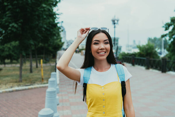 attractive and asian woman with glasses smiling and looking away  