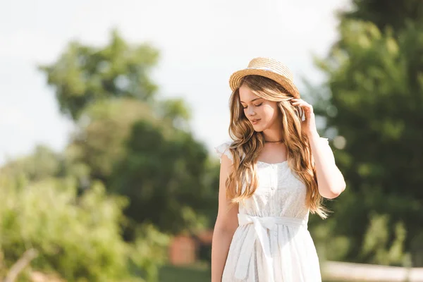 Menina Bonita Vestido Branco Tocando Chapéu Palha Olhando Para Baixo — Fotografia de Stock