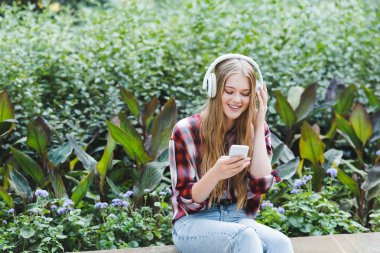 beautiful girl in casual clothes smiling while listening to musing on headphones