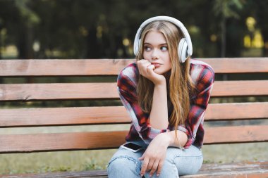 beautiful girl in casual clothes listening to musing on headphones and looking away