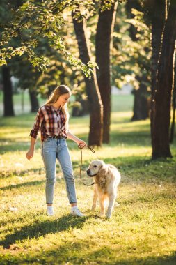 çayırda altın retriever ile yürüyen rahat giysiler içinde kız tam uzunlukta görünümü 