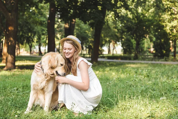 Hermosa Chica Vestido Blanco Sombrero Paja Acariciando Golden Retriever Mientras —  Fotos de Stock