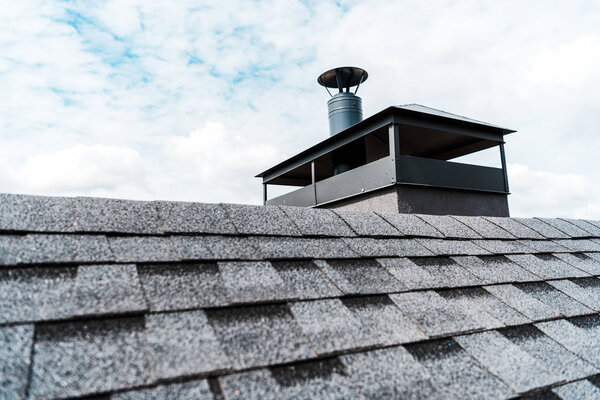 selective focus of modern chimney on rooftop of house 