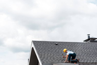 çatı tamir ederken çekiç tutan kask tamircisi 