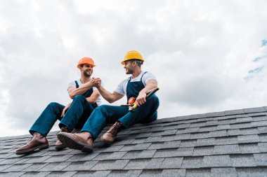 çatıda otururken el ele tutuşan kask mutlu handymen 