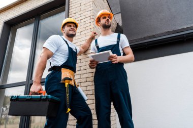 dijital tablet ile iş arkadaşınızın yanında yakışıklı handyman tutan araç kutusu düşük açı görünümü 