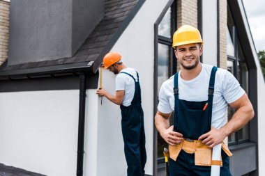 iş arkadaşı yakınında üniformalı mutlu handyman seçici odak 