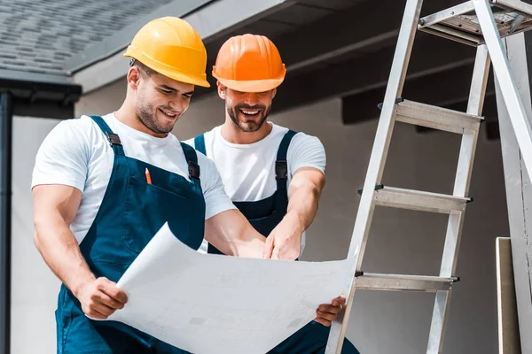 Arquitectos Felices Cascos Mirando Papel Sonriendo Cerca Escalera — Foto de Stock